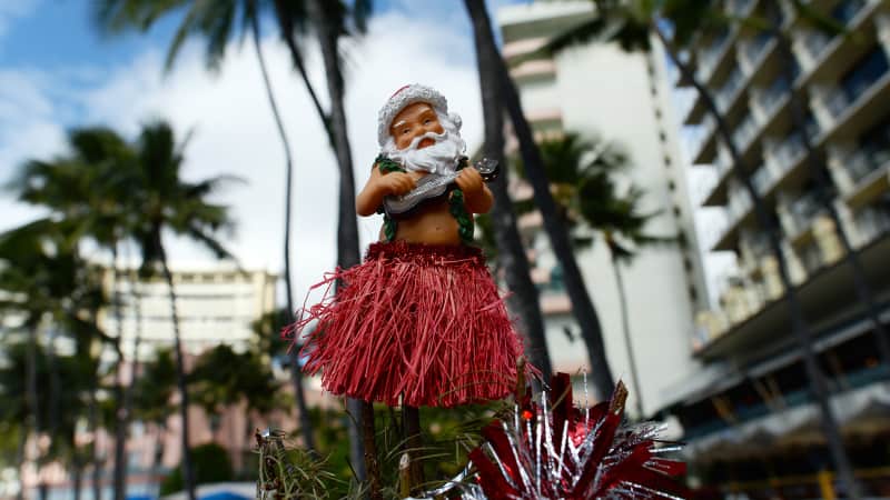 A Hawaiian Santa ornament sits atop a Christmas tree at Waikiki beach in Honolulu on December 25, 2013. AFP PHOTO/Jewel SAMAD (Photo credit should read JEWEL SAMAD/AFP/Getty Images)