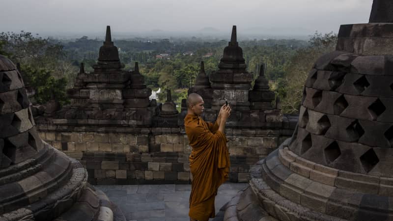 A Buddhist monk takes a picture of Buddha statue at Borobudur temple during celebrations for Vesak Day.