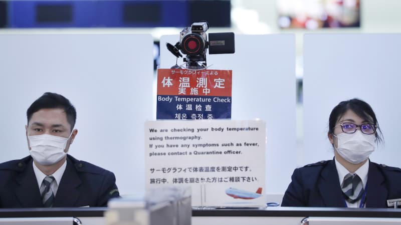 Officers at a health screening station in Tokyo's Narita Airport observe passengers arriving on a flight from Wuhan, China on January 16.
