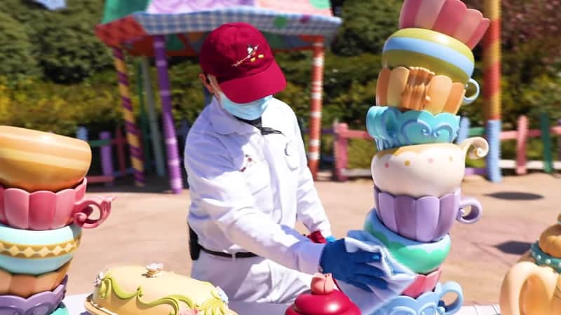 A worker sanitizes the Alice in Wonderland walk-through maze. 