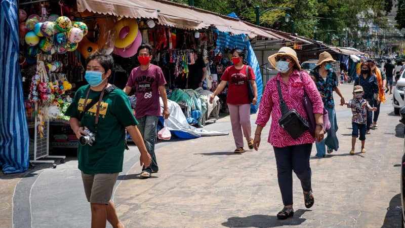 Visitors wearing face masks, amid concerns over the spread of the COVID-19 coronavirus, walk along street shops in Hua Hin beach in Thailand on May 19, 2020