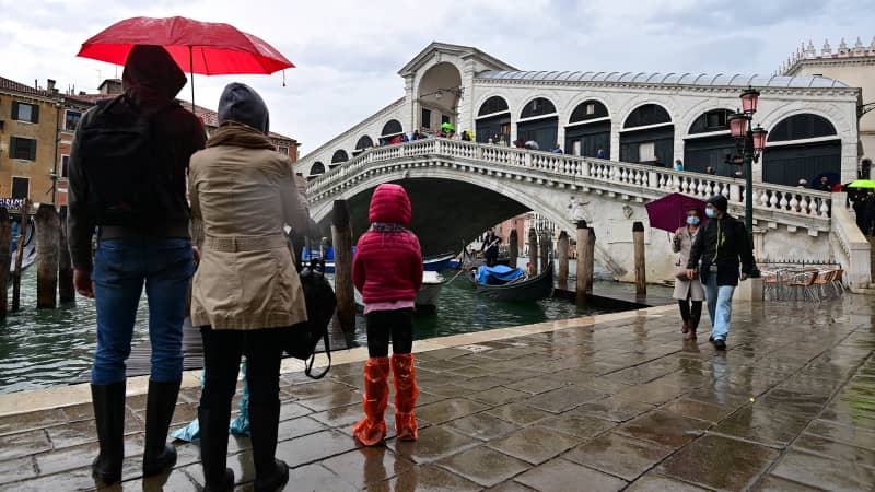 Tourists await the high tide in the center of Venice. 