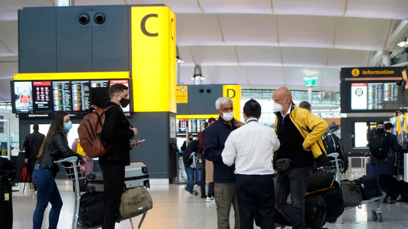 Travelers wearing a face mask or covering stand at check-in desks at Terminal 2 of Heathrow Airport in  London on December 21 as a string of countries around the world banned travellers arriving from the UK.