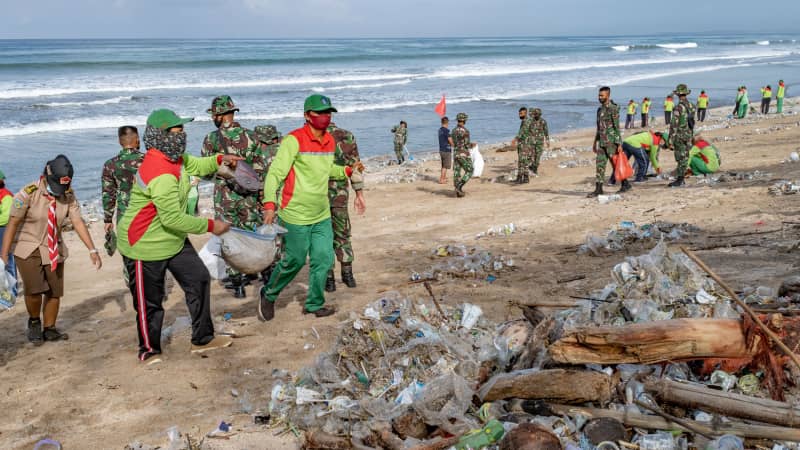Workers clean up piles of debris and plastic waste brought in by strong waves at Kuta Beach in Bali, Indonesia, on January 1, 2021.