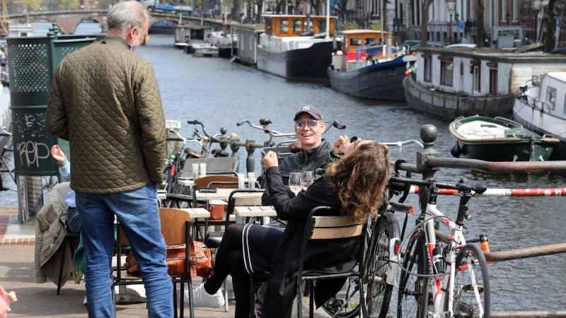 Customers sit on a terrace alongside a canal in Amsterdam, on April 28, 2021,