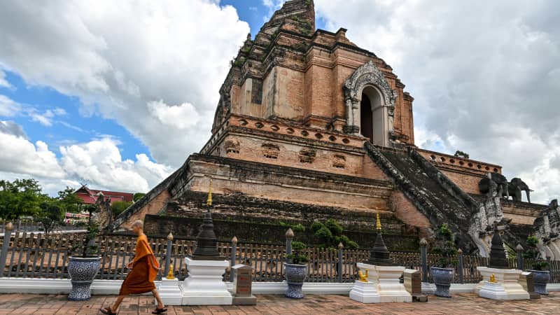 A novice monk walks past Wat Chedi Luang Buddhist temple in Chiang Mai on October 31, 2020.