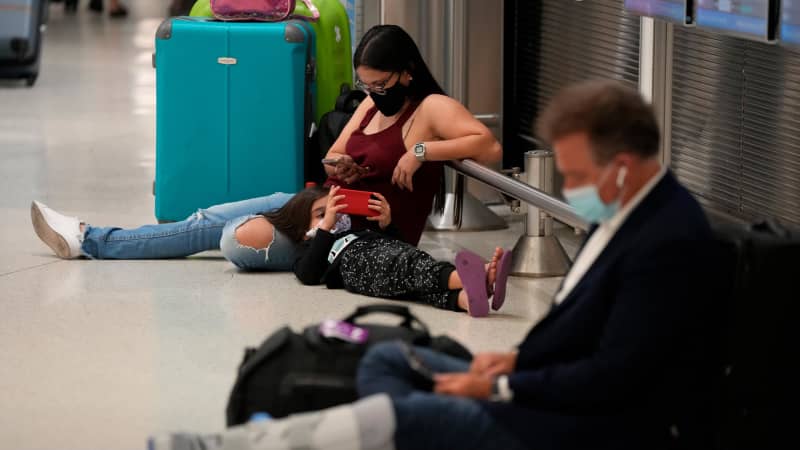A woman and child wait for their flight alongside another traveler at Miami International Airport on Monday, December 27.