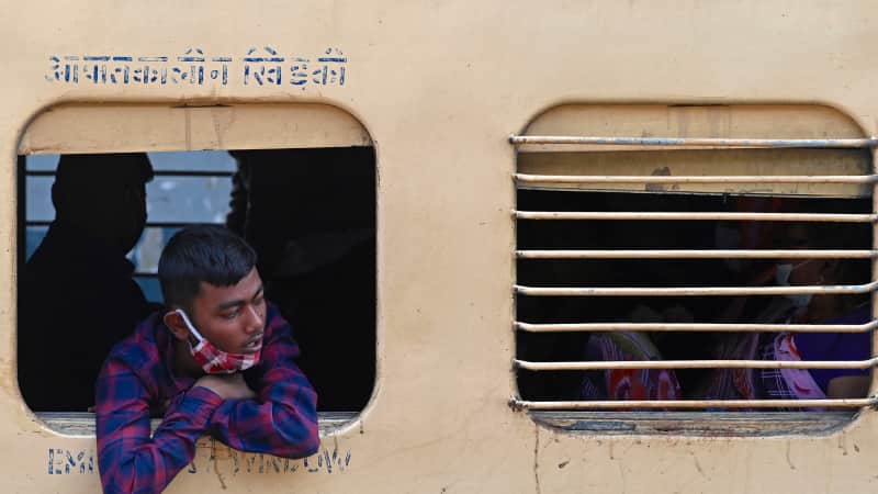 A passenger looks out from the window of a long-distance train at a railway station in Mumbai on January 17, 2022.