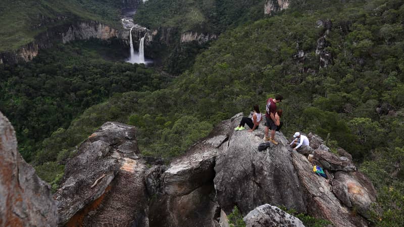 Visitors rest on a rock formation near the Saltos do Rio Preto waterfall in Chapada dos Veadeiros. 