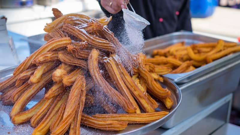 Delicious churros sticks are deep fried and dusted with powdered sugar.