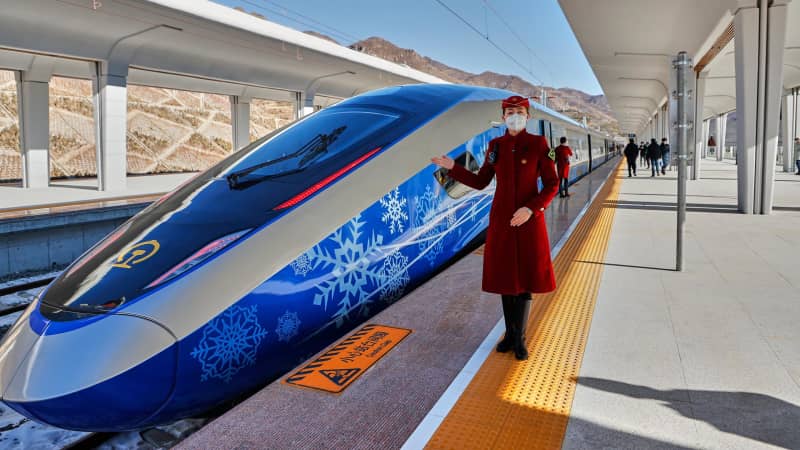 A train attendant poses beside an "intelligent" Fuxing bullet train on January 6, 2022 in China. 