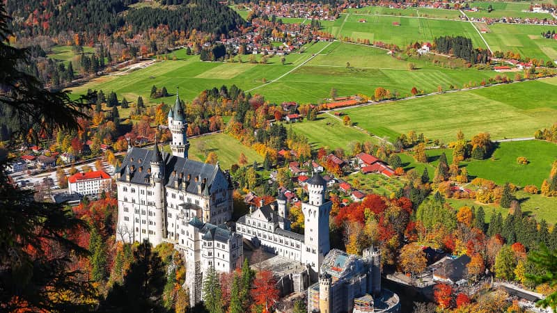 An aerial view of famous Neuschwanstein Castle surrounded by Bavarian autumn glory.