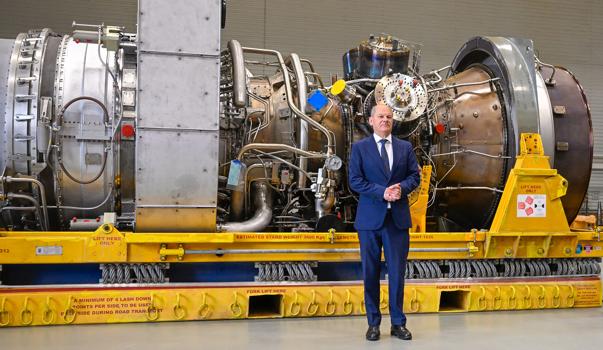 German Chancellor Olaf Scholz stands in front of a turbine of the Nord Stream 1 pipeline during a visit on August 3, to Siemens Energy in Muelheim, Germany, where the engine is stored after maintenance work in Canada.