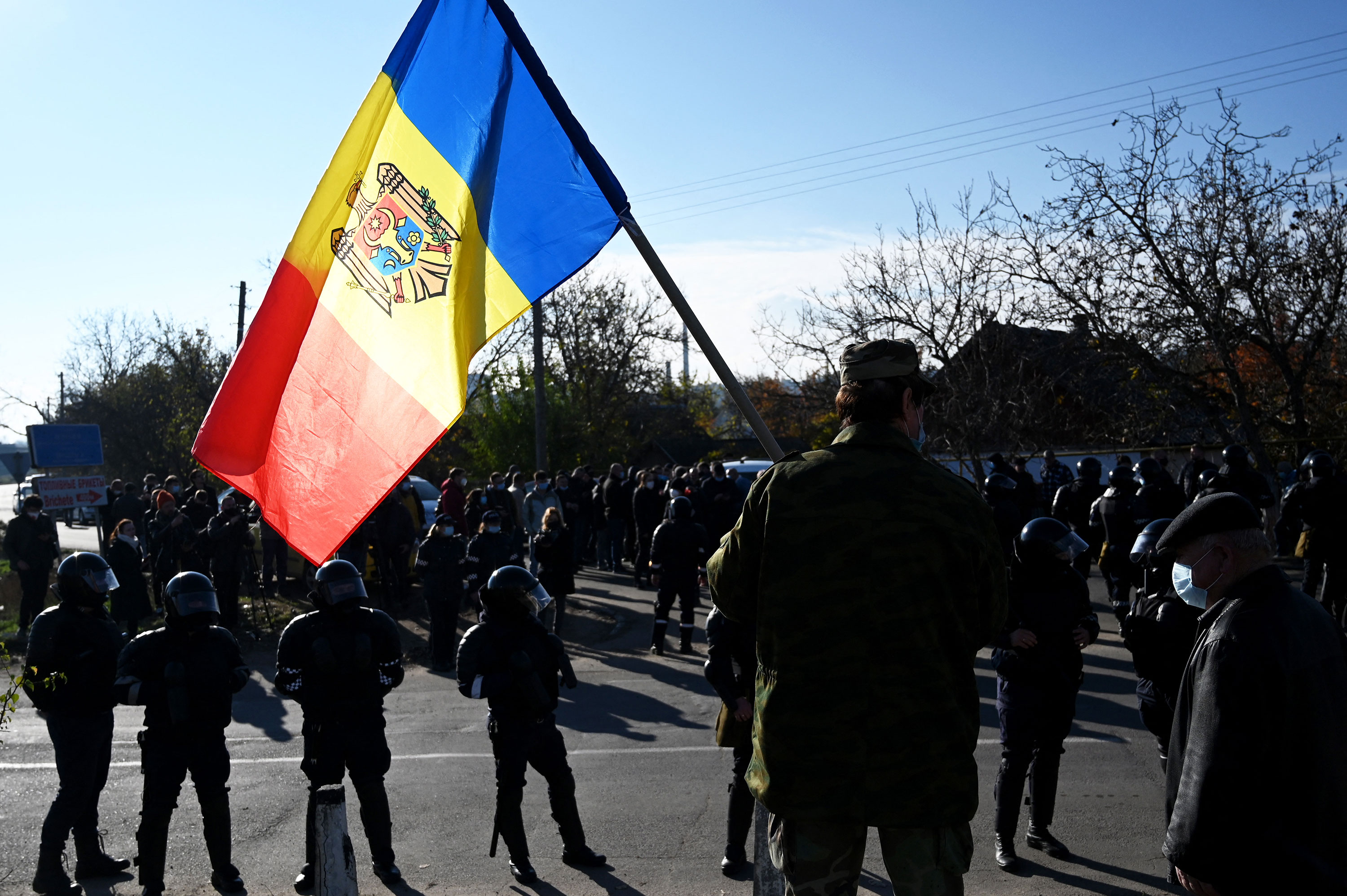 A man holds Moldovan national flag as special police officers patrol a street near a polling station during the second round of Moldova's presidential election in the town of Varnita in 2020. 