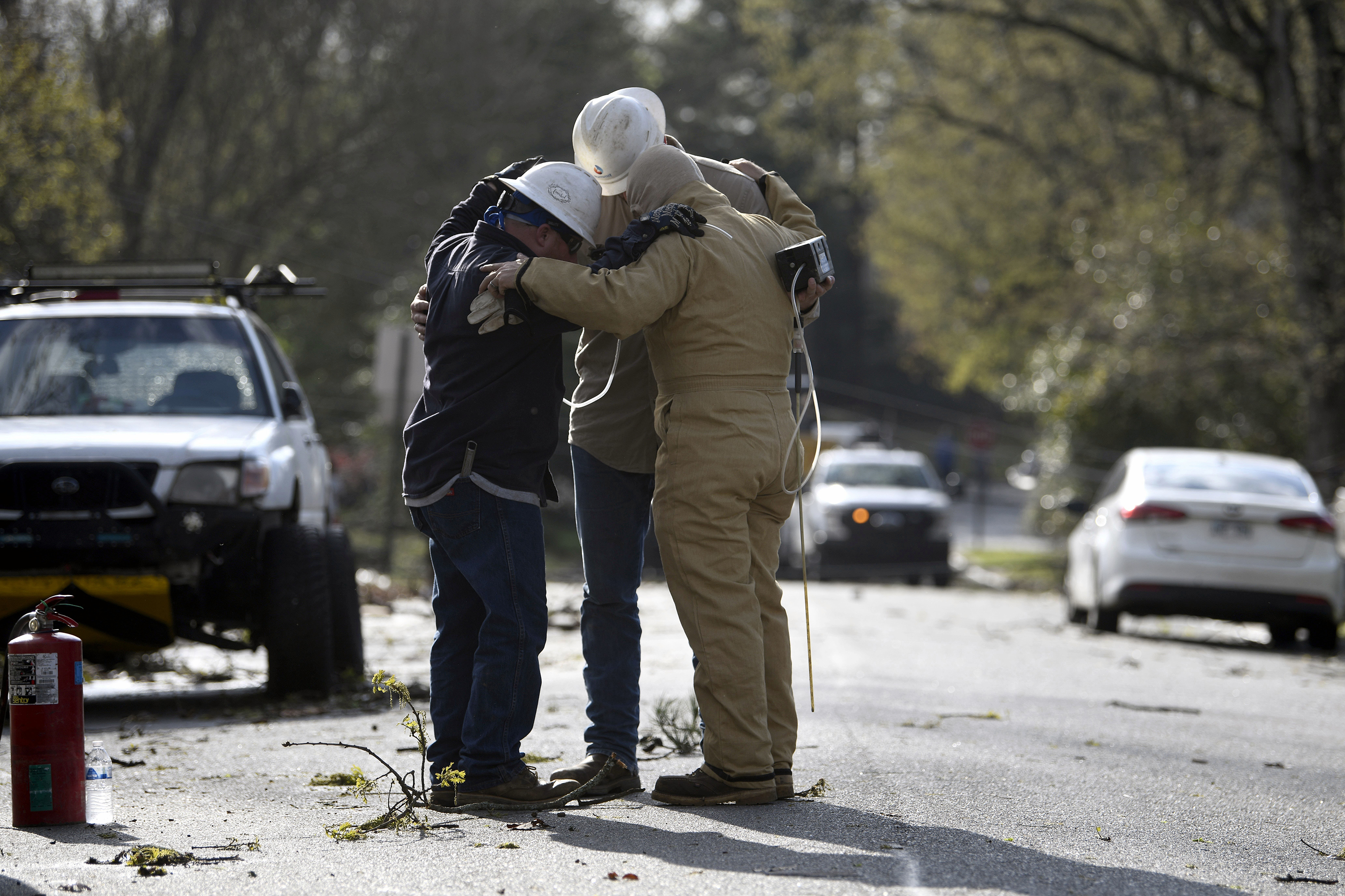 A team from Summit Energy say a prayer together before investigating a burst gas line in Cammack Village after a tornado swept through the area Friday, March 31,  in Little Rock, Arkansas. 