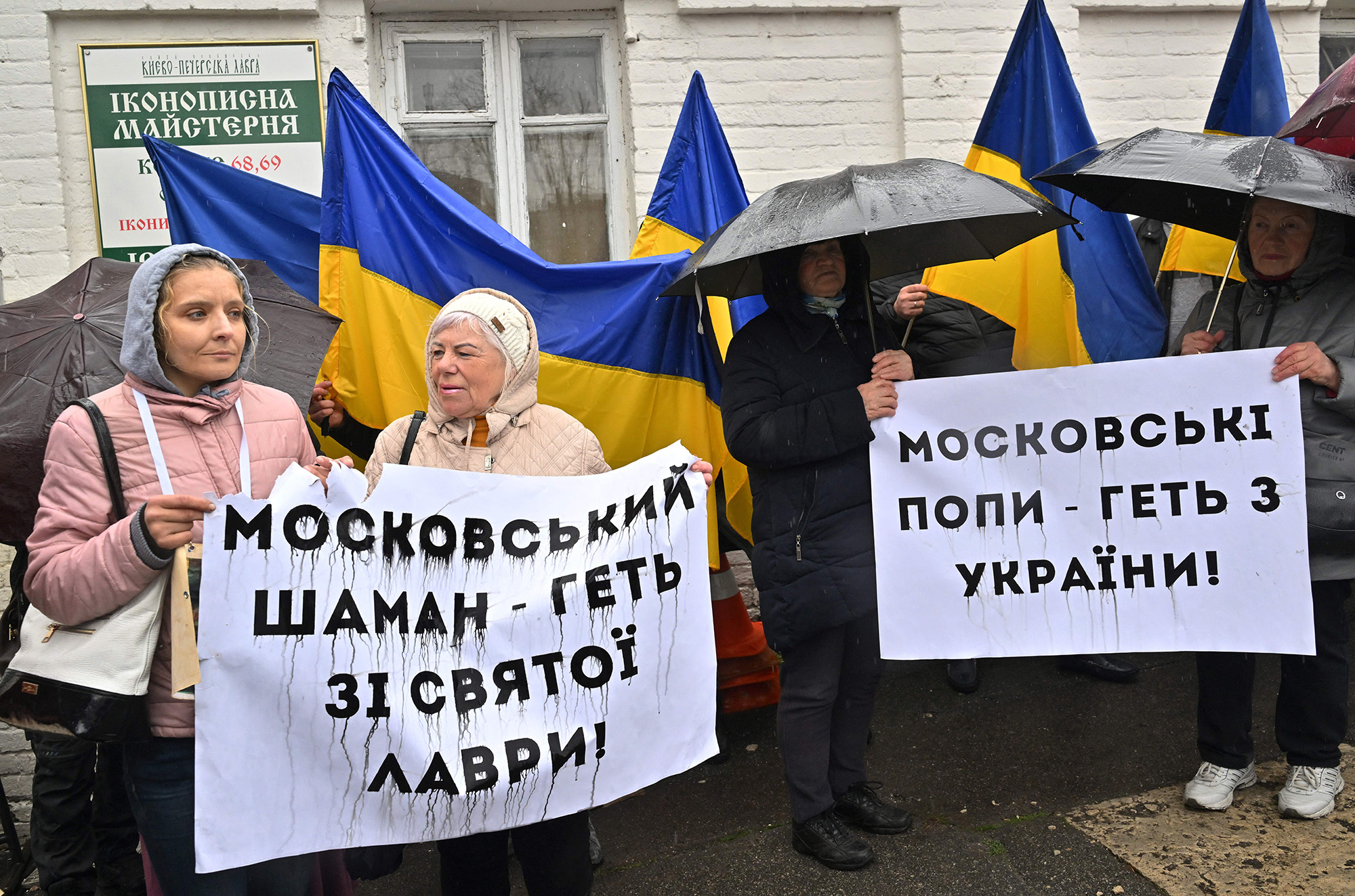 People hold placards reading "Moscow priests get away from Ukraine!", right, and "Moscow shaman get away from holy Lavra!" as they rally at the entrance to the Kyiv-Pechersk Lavra in Kyiv, Ukraine, on March 28.