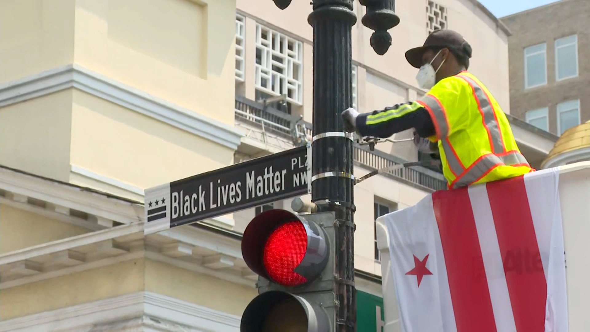A man mounts the new "Black Lives Matter Plz NW" street sign to a pole in Washington, on June 5.