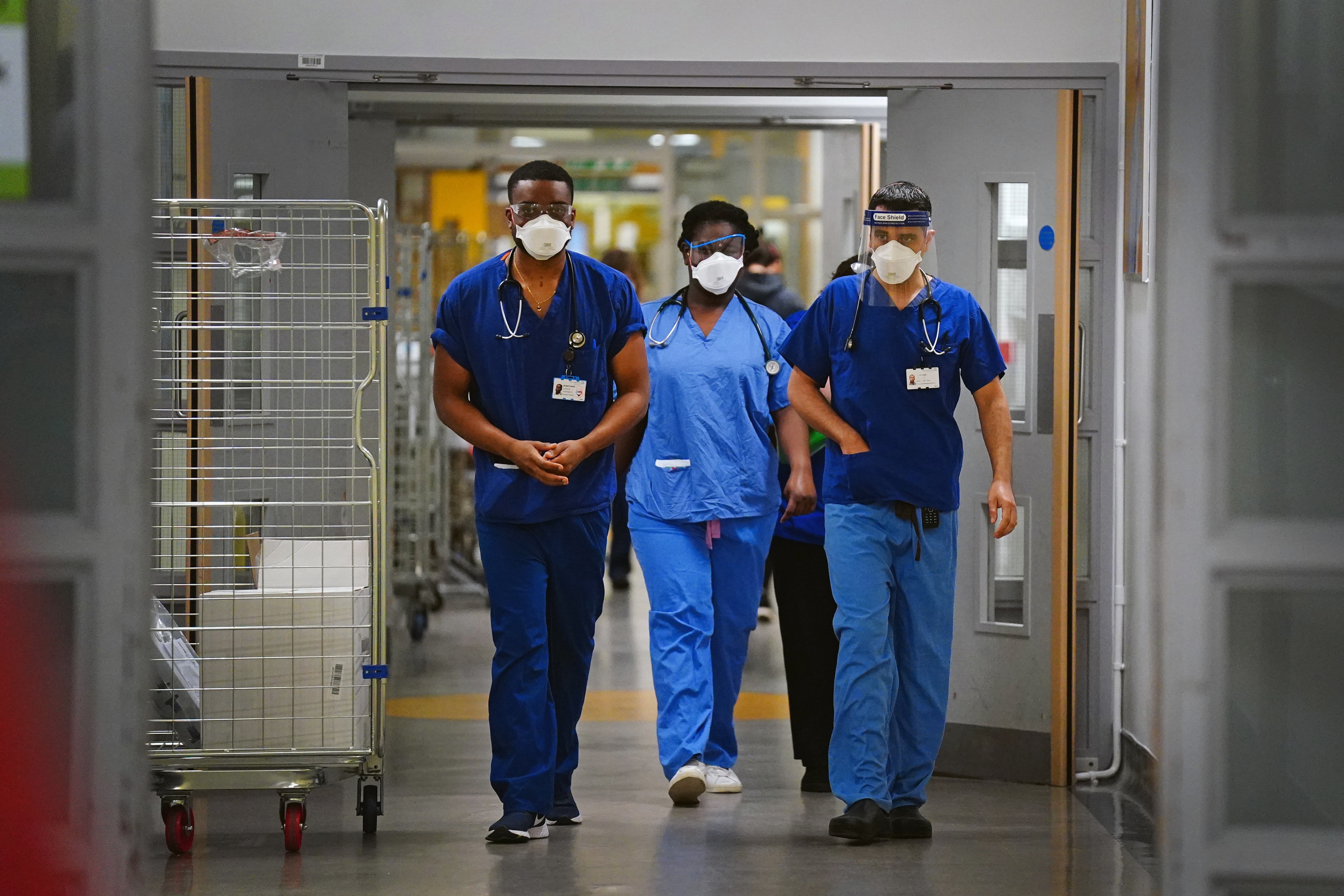 Medical staff wearing FFP3 face masks walk along a corridor at King's College Hospital, in south east London. Picture date: Tuesday December 21, 2021. 