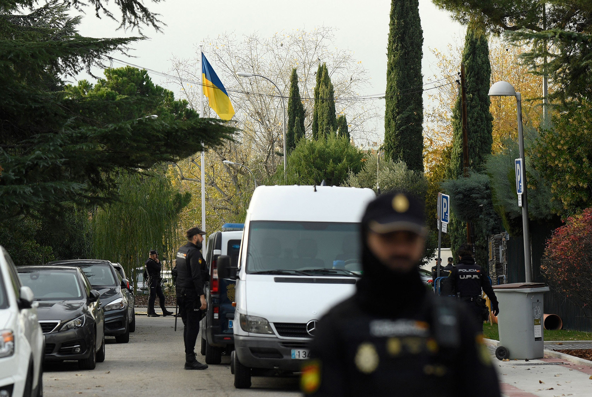 Spanish policemen stand next to an Ukrainian flag while securing the area after a letter bomb explosion at the Ukraine's embassy in Madrid, Spain, on November 30.