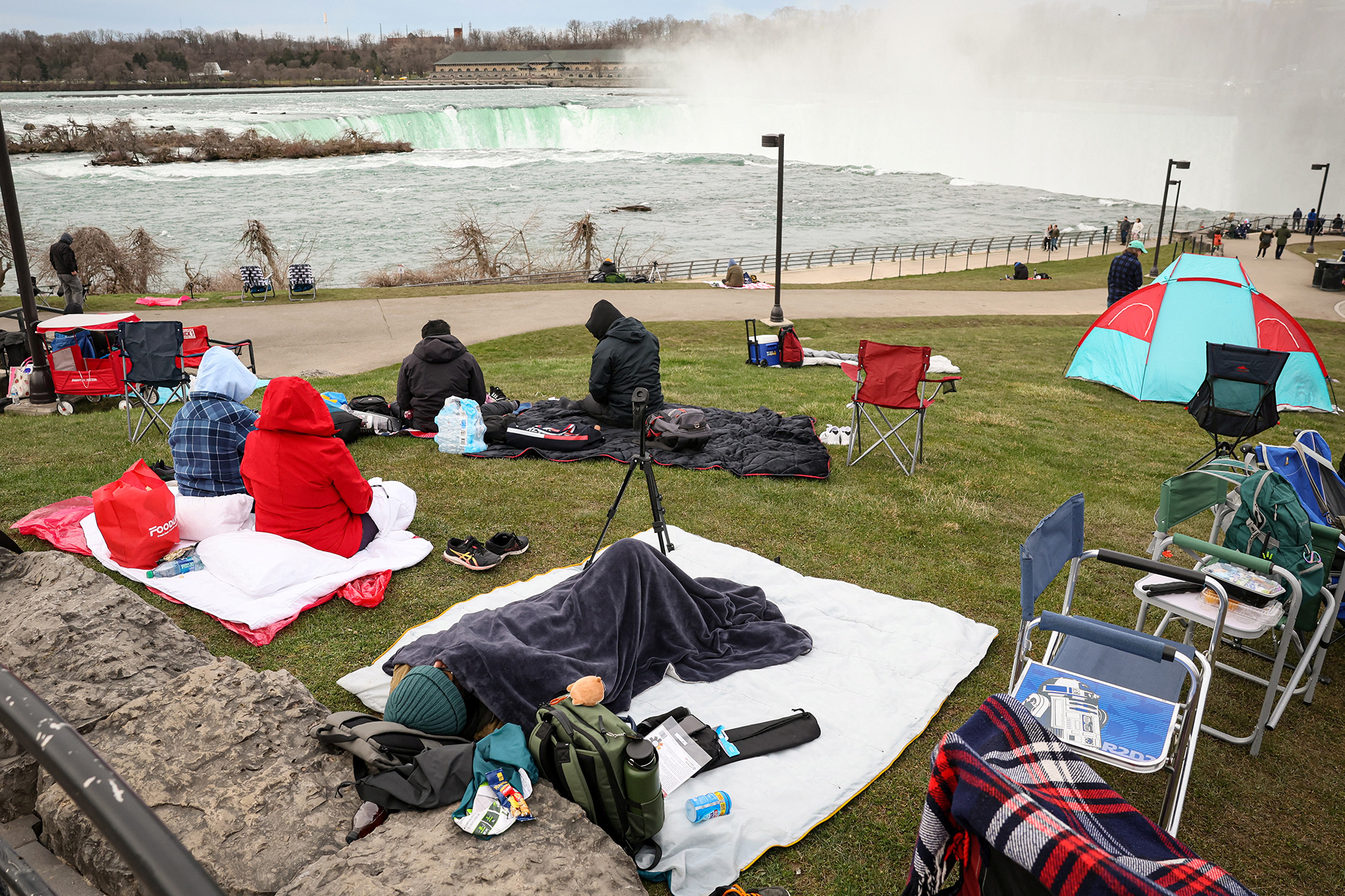 Tourists sleep next to the Horseshoe Falls ahead of the eclipse in Niagara Falls, New York.