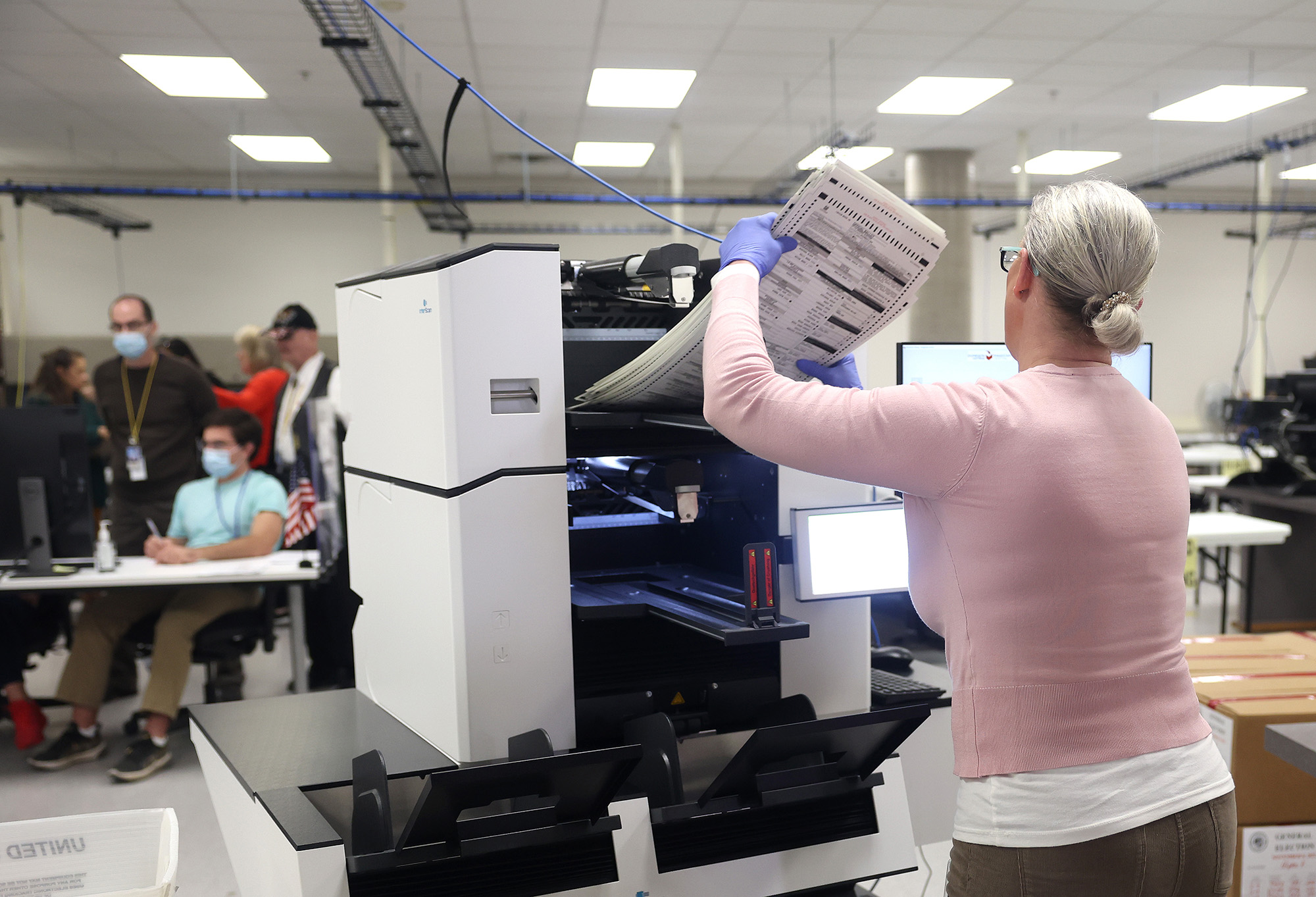 An election worker inserts ballots into a scanning machine at the Maricopa County Tabulation and Election Center in Phoenix on November 10.