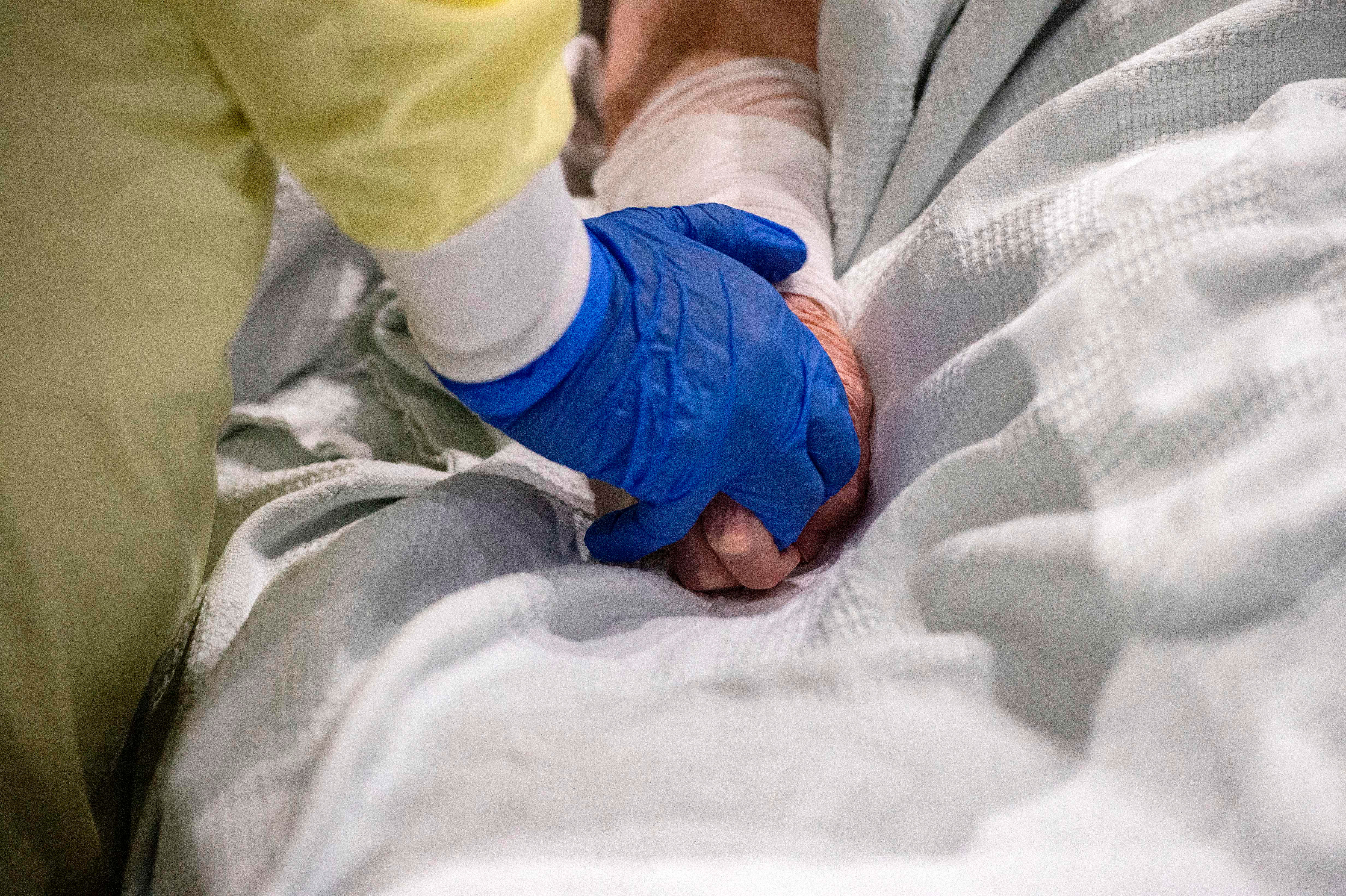 A medical worker cares for and comforts a patient who is suffering from Covid-19 at UMASS Memorial DCU Center Field Hospital in Worcester, Massachusetts, on January 13.