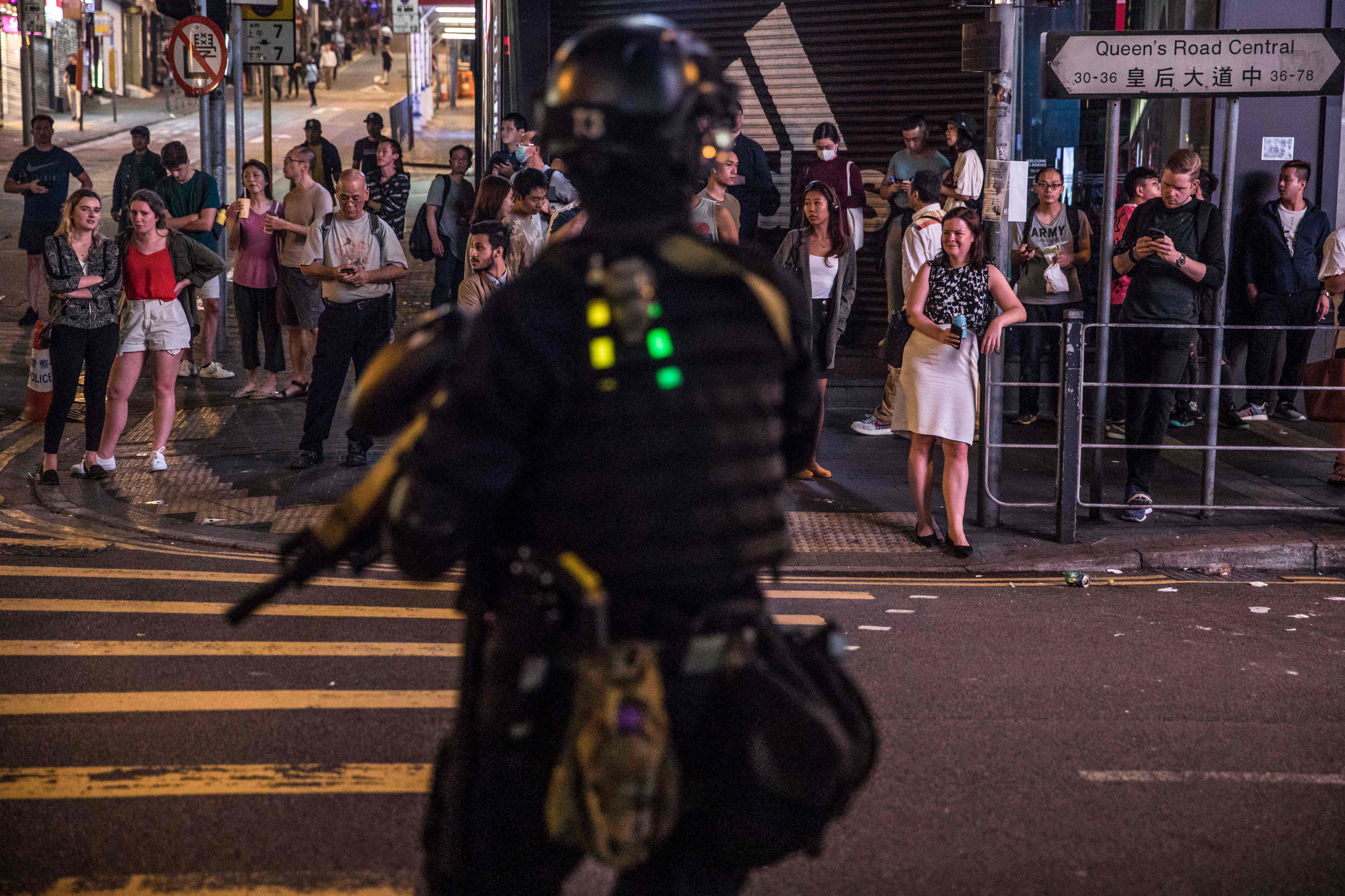 A riot policeman stands before pedestrians after clearing protesters from the Central district in Hong Kong.
