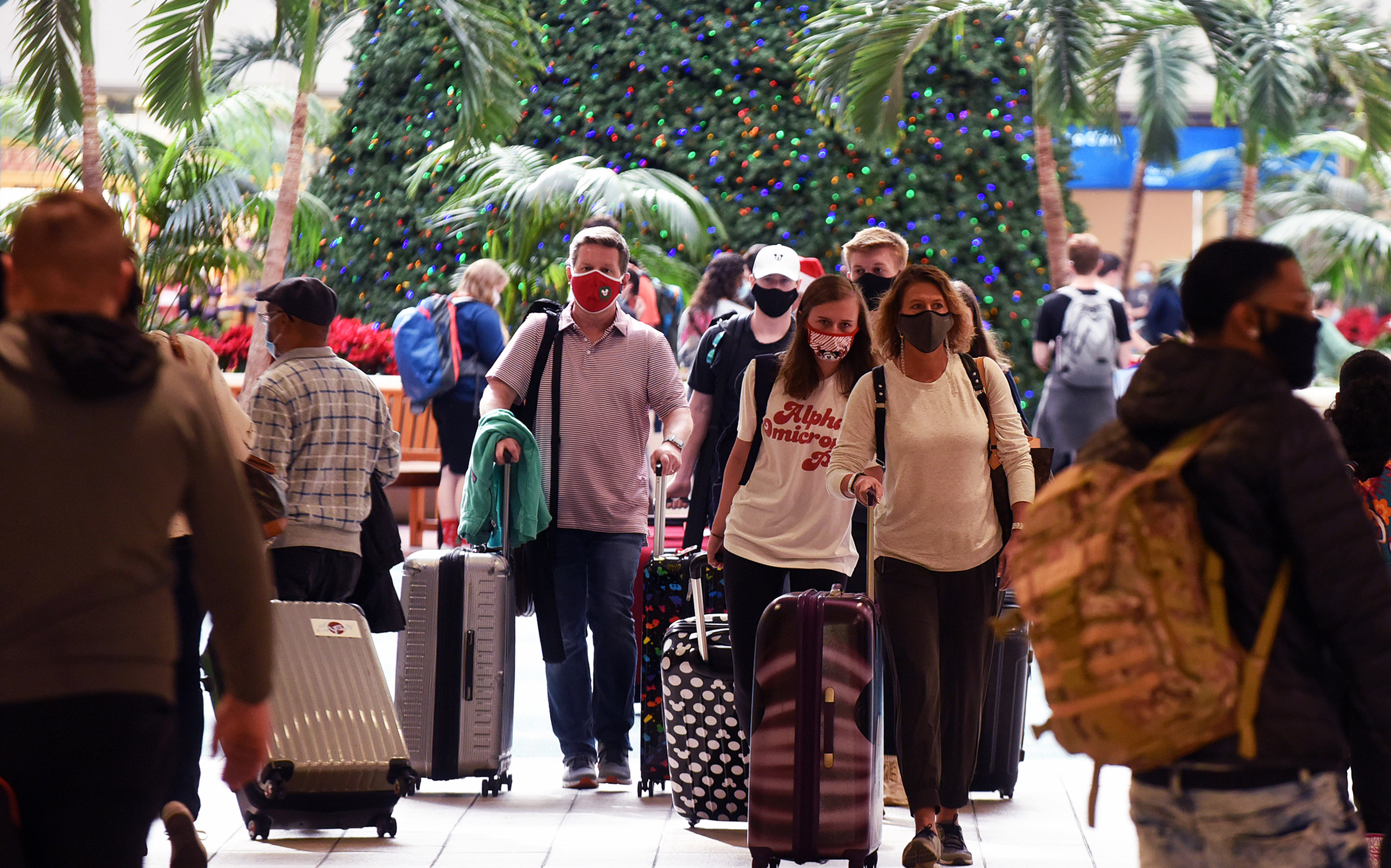 Travelers wearing face masks arrive at Orlando International Airport in Florida, on December 24.