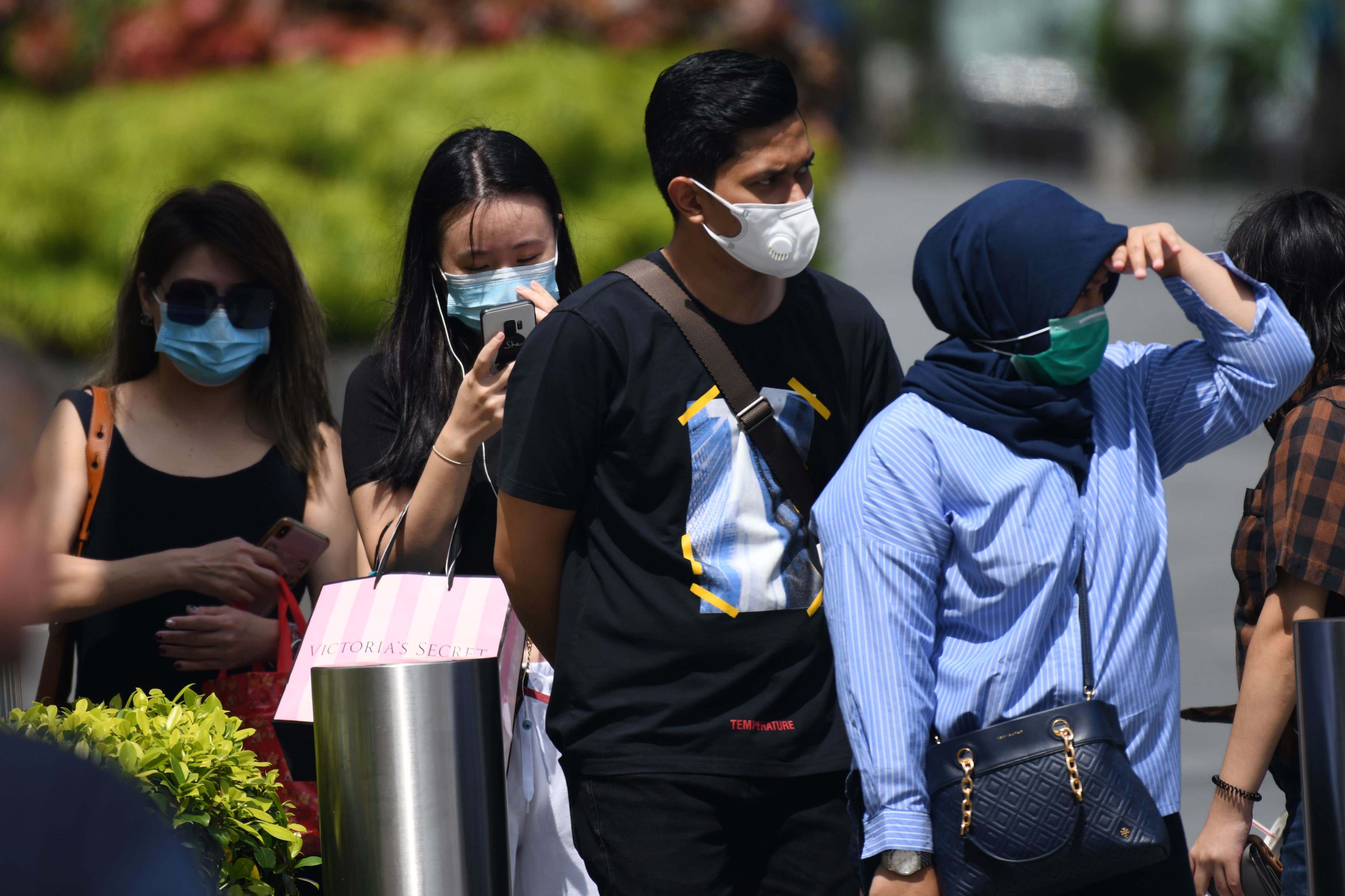 People wearing protective face masks wait at a pedestrian crossing in Singapore on February 4, 2020. Photo by ROSLAN RAHMAN/AFP via Getty Images 