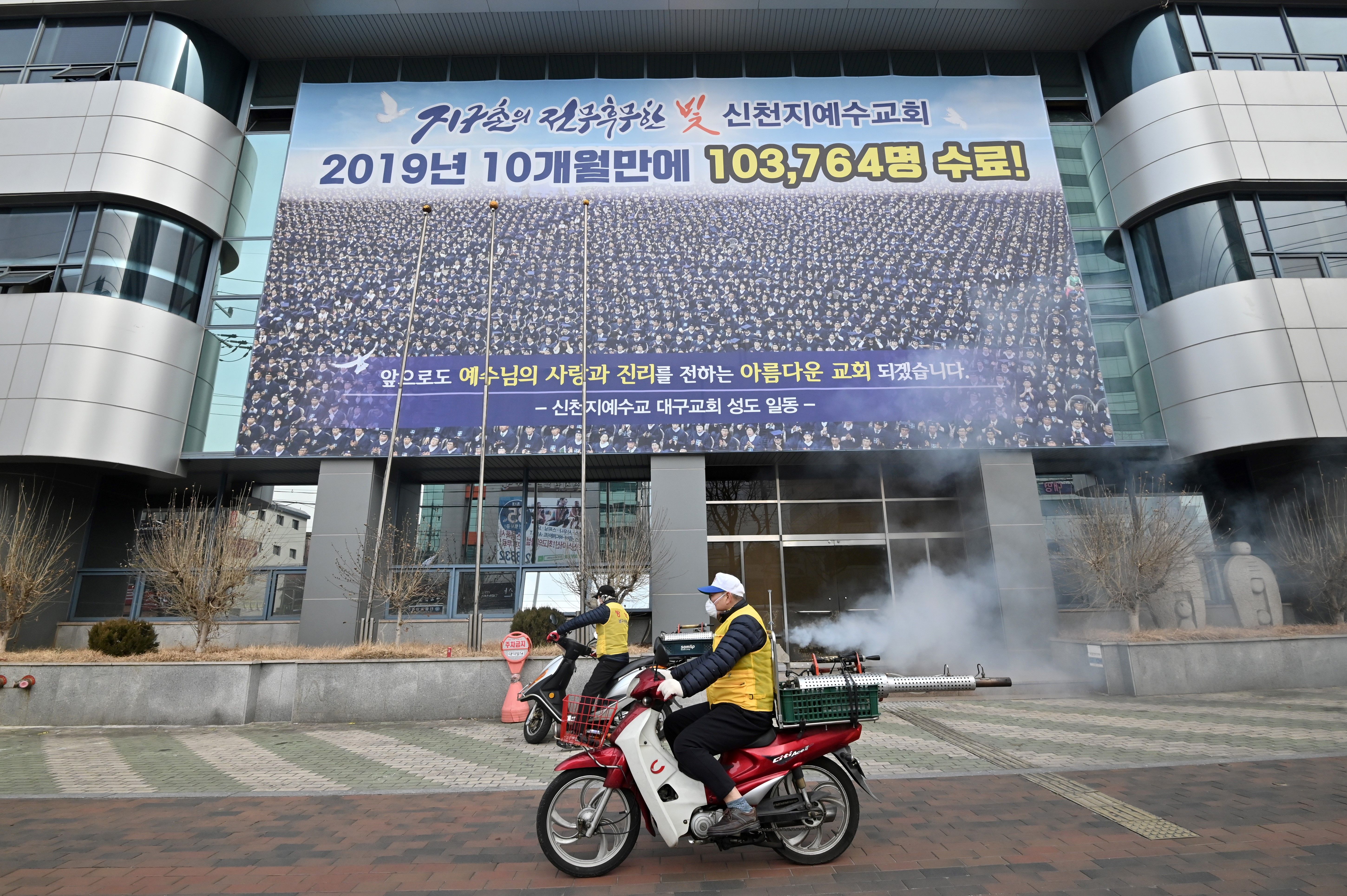 South Korean health officials spray disinfectant in front of the Daegu branch of the Shincheonji religious group in the southeastern city of Daegu.