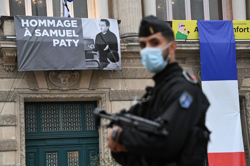 A police officer stands in front of a portrait of Samuel Paty, in Montpellier, France, on October 21. Paty was killed earlier this month.