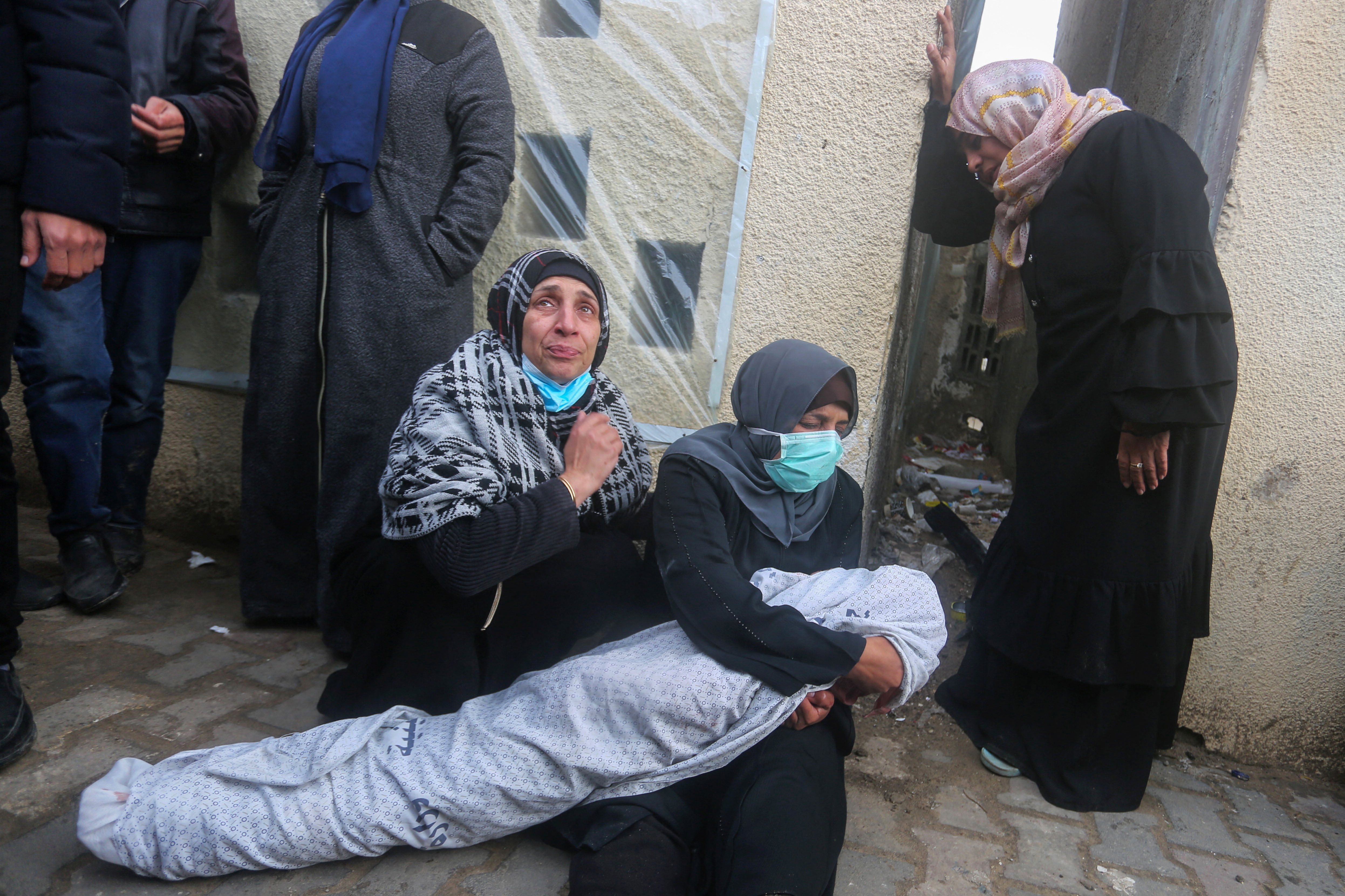 Relatives mourn by a shrouded body after an Israeli airstrike hit the Baraka family home in Deir al-Balah, Gaza, on February 18.