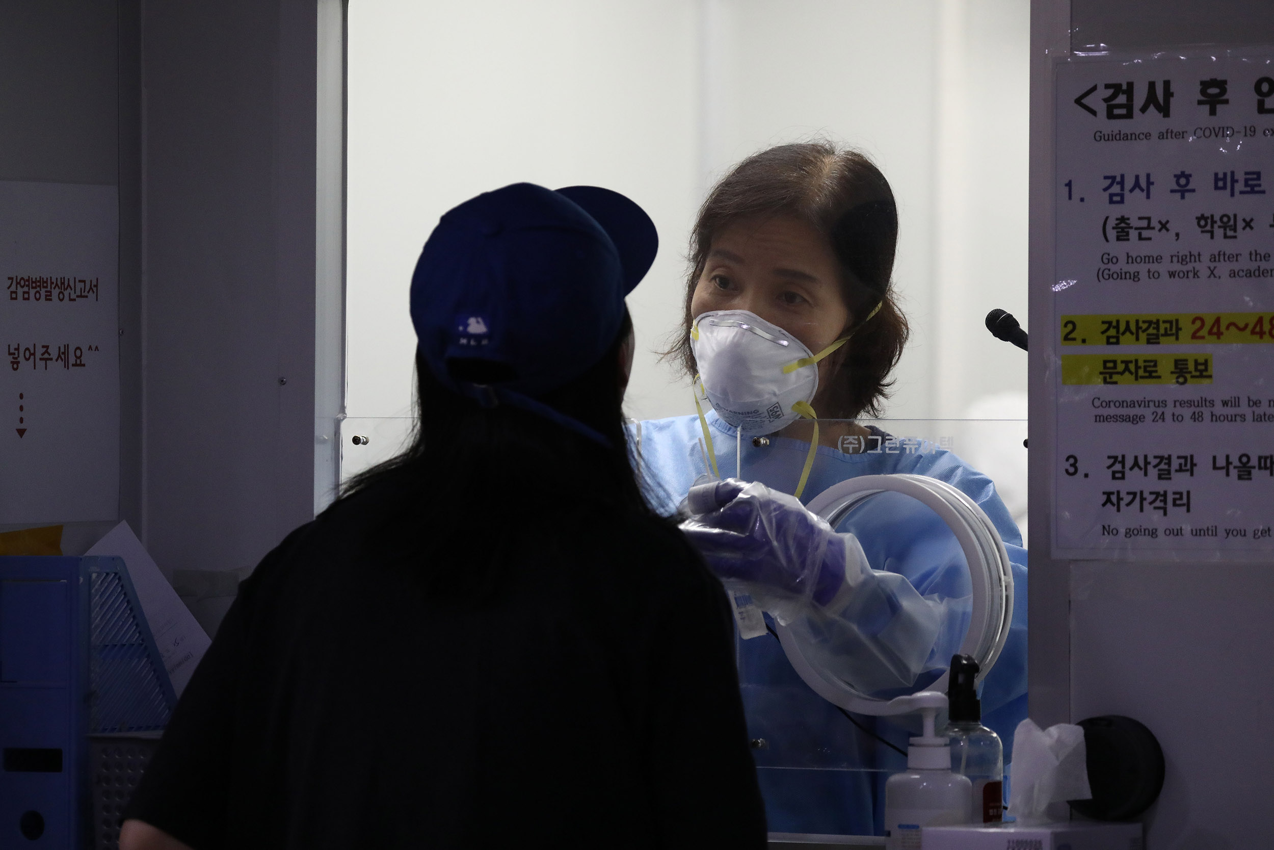 A medical worker takes samples from a woman at a Covid-19 test facility on August 26, in Seoul, South Korea. 