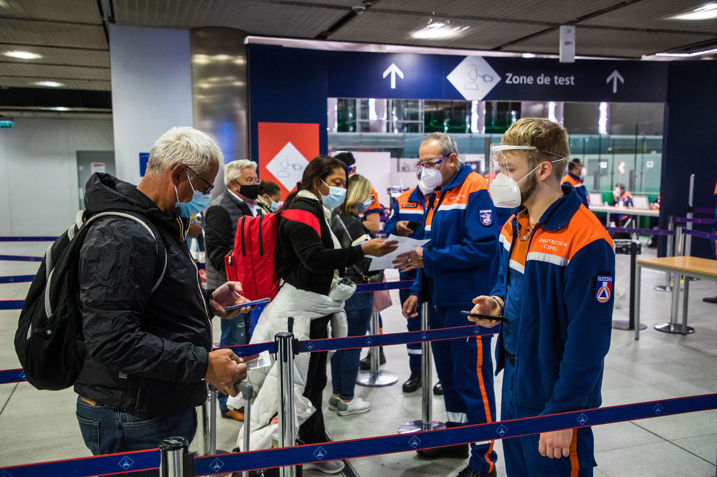 Health workers greet passengers arriving from an international flight before testing for Covid-19 tested at Paris-Charles de Gaulle airport in Roissy, France, on Tuesday.