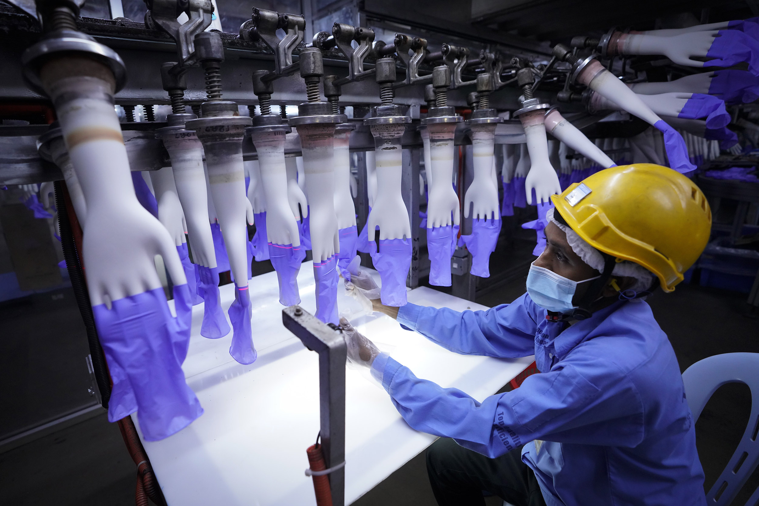 A worker inspects disposable gloves at the Top Glove factory in Shah Alam on the outskirts of Kuala Lumpur, Malaysia, on Wednesday, August 26.  