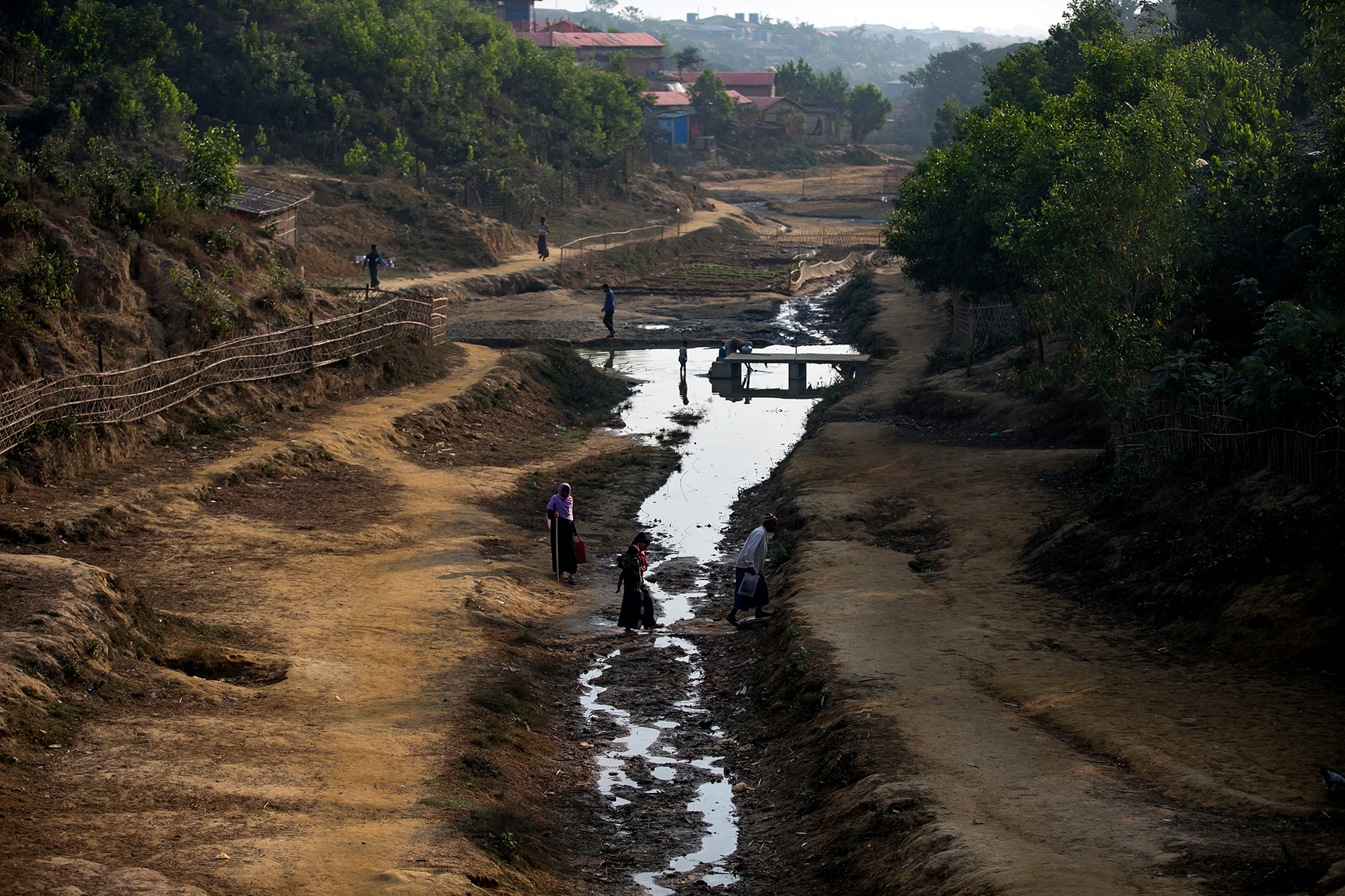 People cross a stream in a Rohingya refugee camp on January 23 in Cox's Bazar, Bangladesh. 