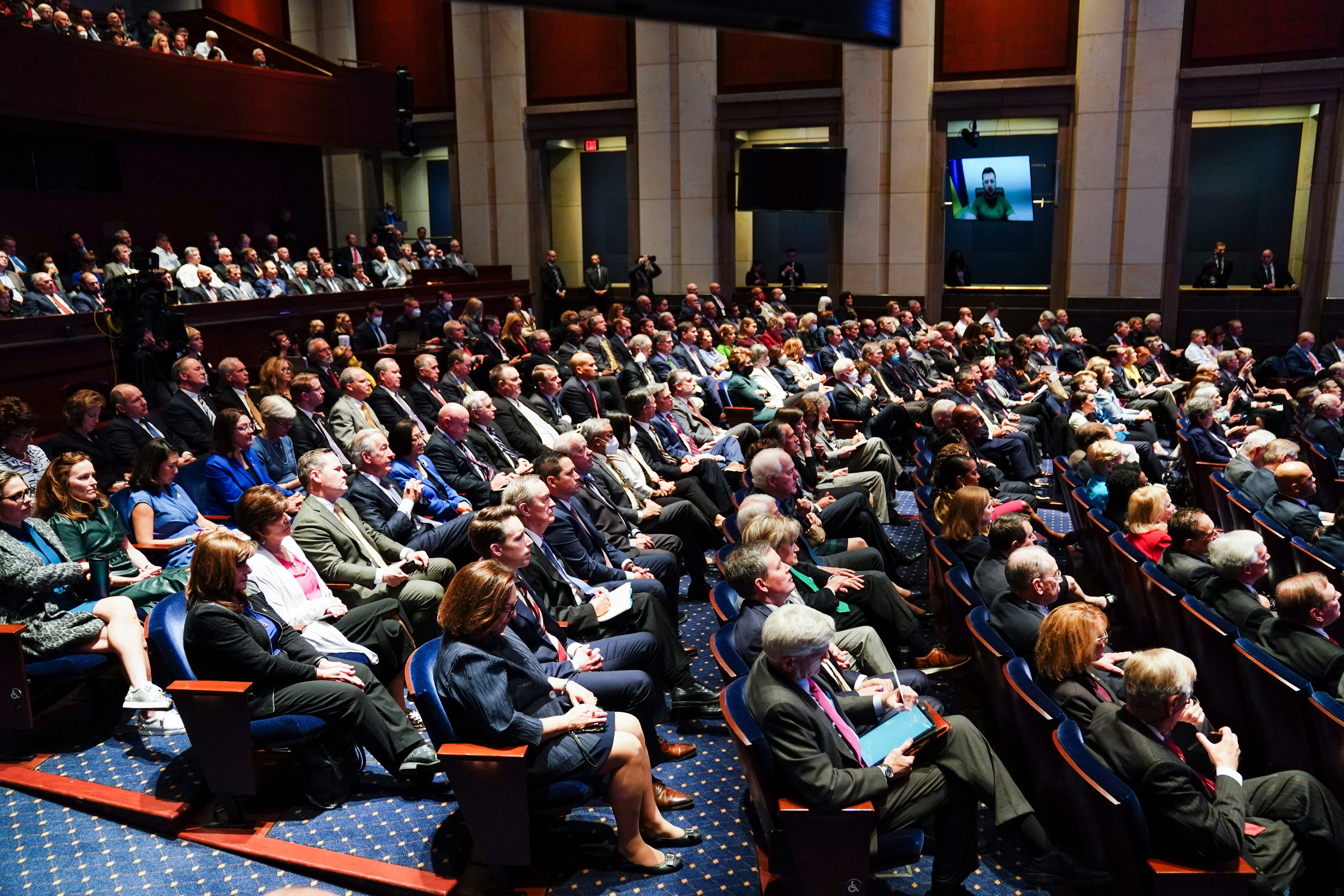 Members of the US Congress listen during a virtual address by Ukrainian President Volodymyr Zelensky (on screen) on March 16, 2022, at the US Capitol Visitor Center Congressional Auditorium, in Washington, DC. 