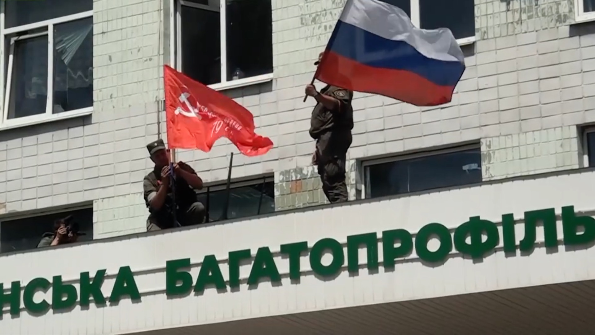 This image released by the People's Militia of the Luhansk People's Republic on July 3, shows their forces with Soviet and Russian national flags on a government building as they capture the city of Lysychansk, in the Luhansk region of eastern Ukraine.