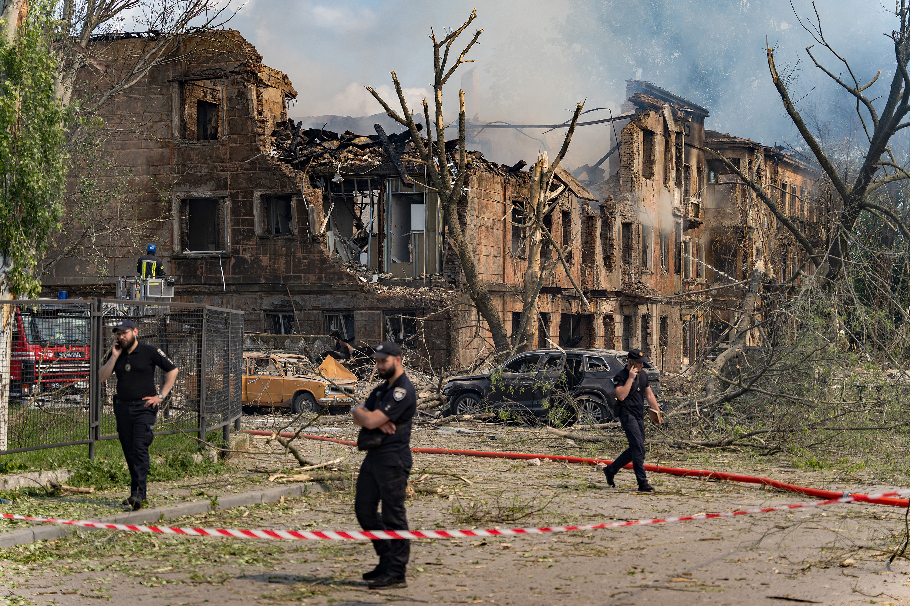 Police officers stand near the site of a missile strike on a hospital, fenced by warning tape on May 26, in Dnipro, Ukraine. 