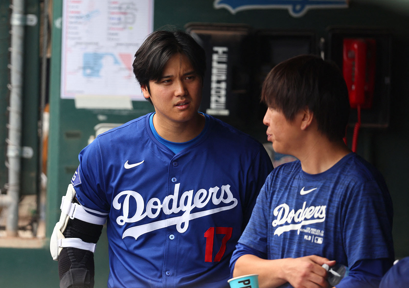 Shohei Ohtani talks with translator Ippei Mizuhara in the dugout against the San Francisco Giants during a spring training baseball game at Camelback Ranch-Glendale on March 12, in Phoenix, Arizona.