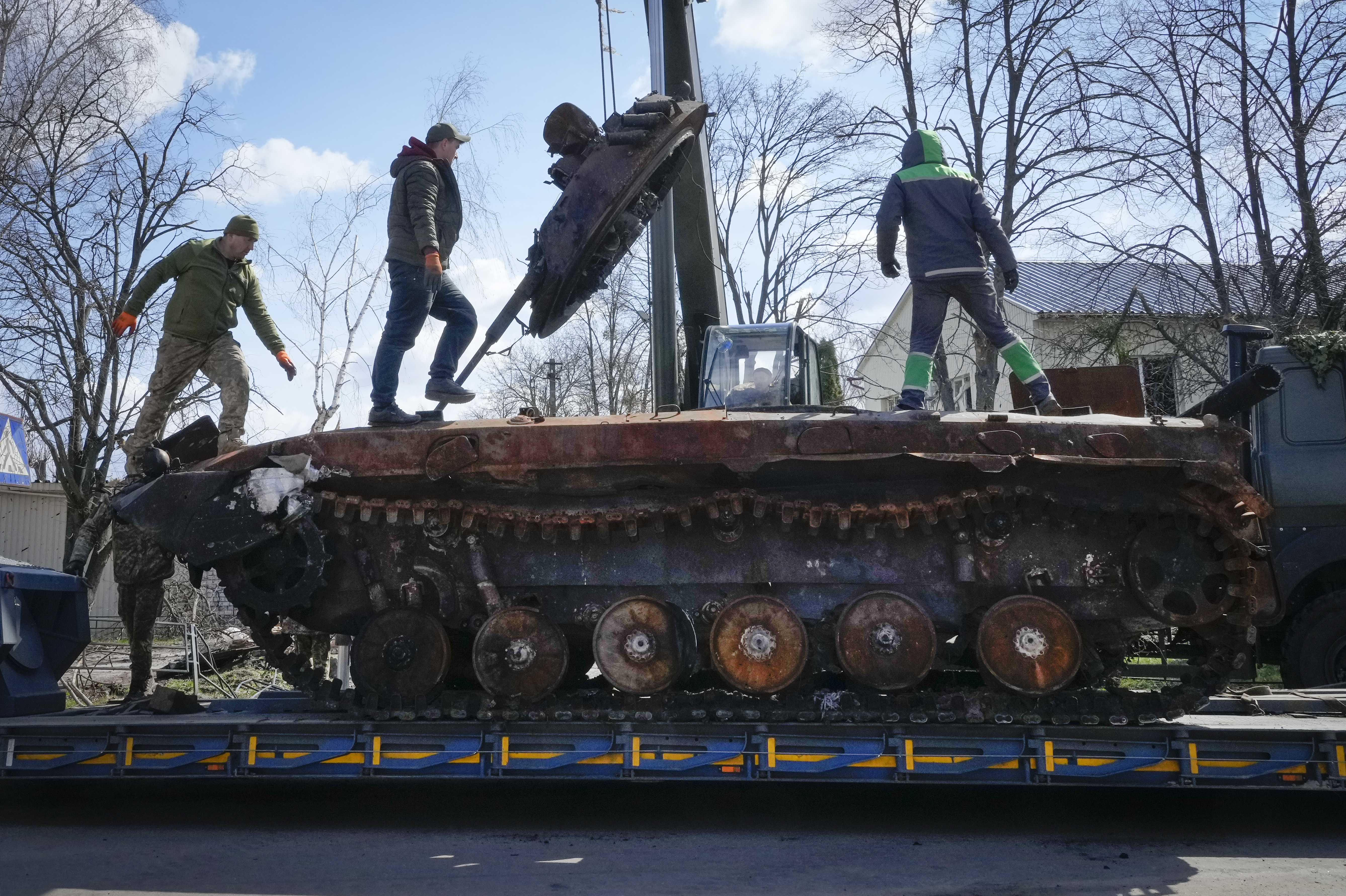 Workers load a destroyed Russian tank onto a platform in the village of Andriyivka, near Kyiv, Ukraine, on April 11. 