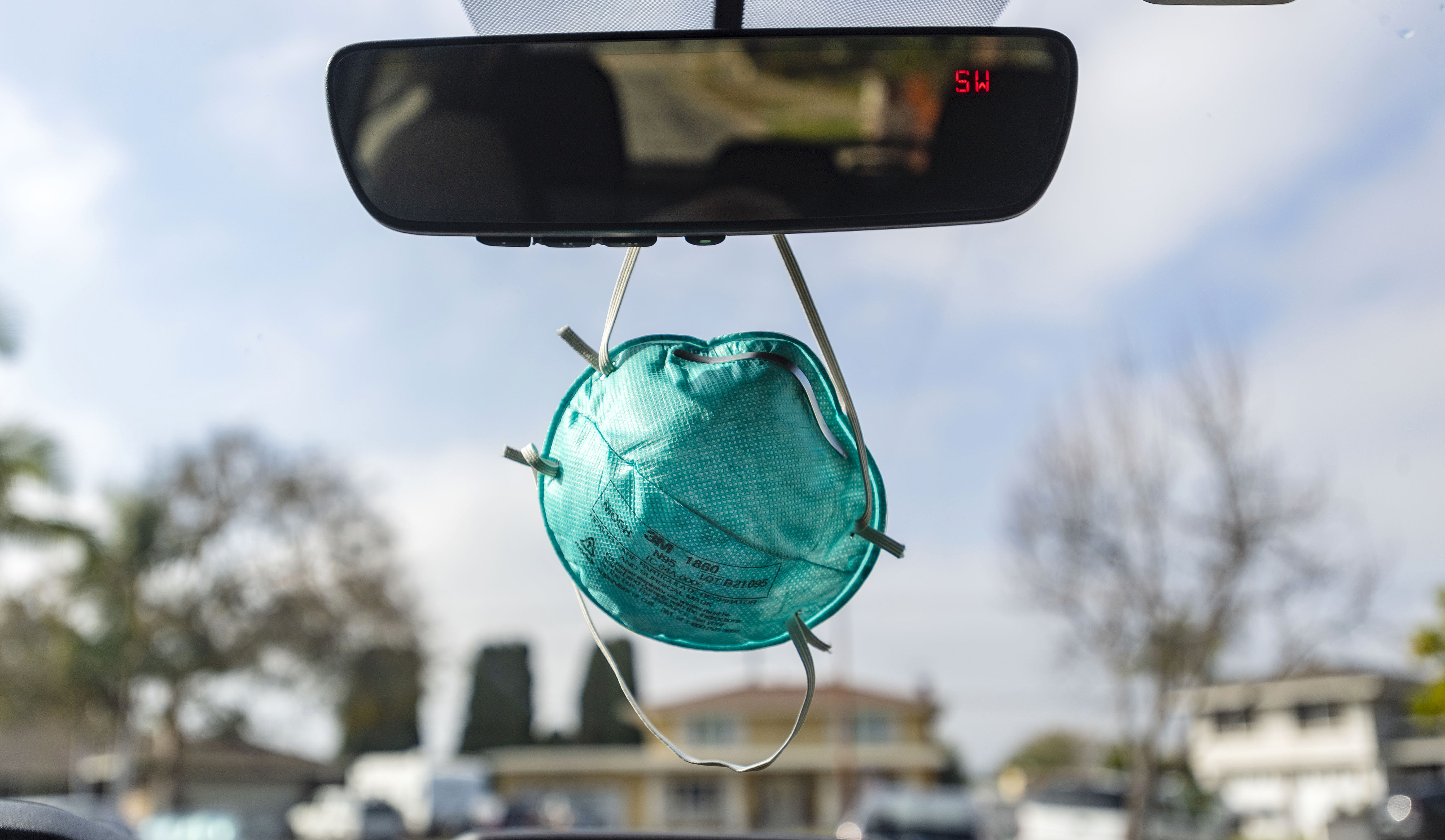 An N95 mask dangles from the rear-view mirror of a car in North Tustin, California last week. 