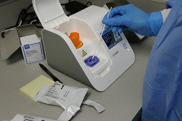 A lab technician dips a sample into the Abbott Laboratories ID Now testing machine at the Detroit Health Center in Detroit, on April 10.