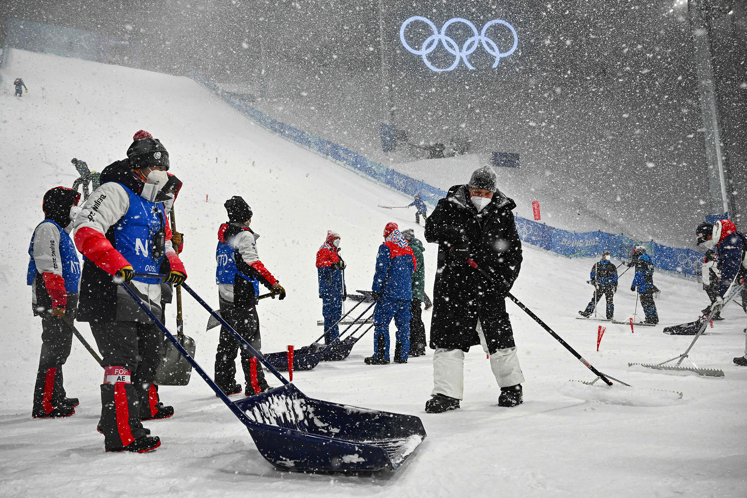 Crew members clear snow from the course ahead of the freestyle skiing women's aerials qualification on February 13. 
