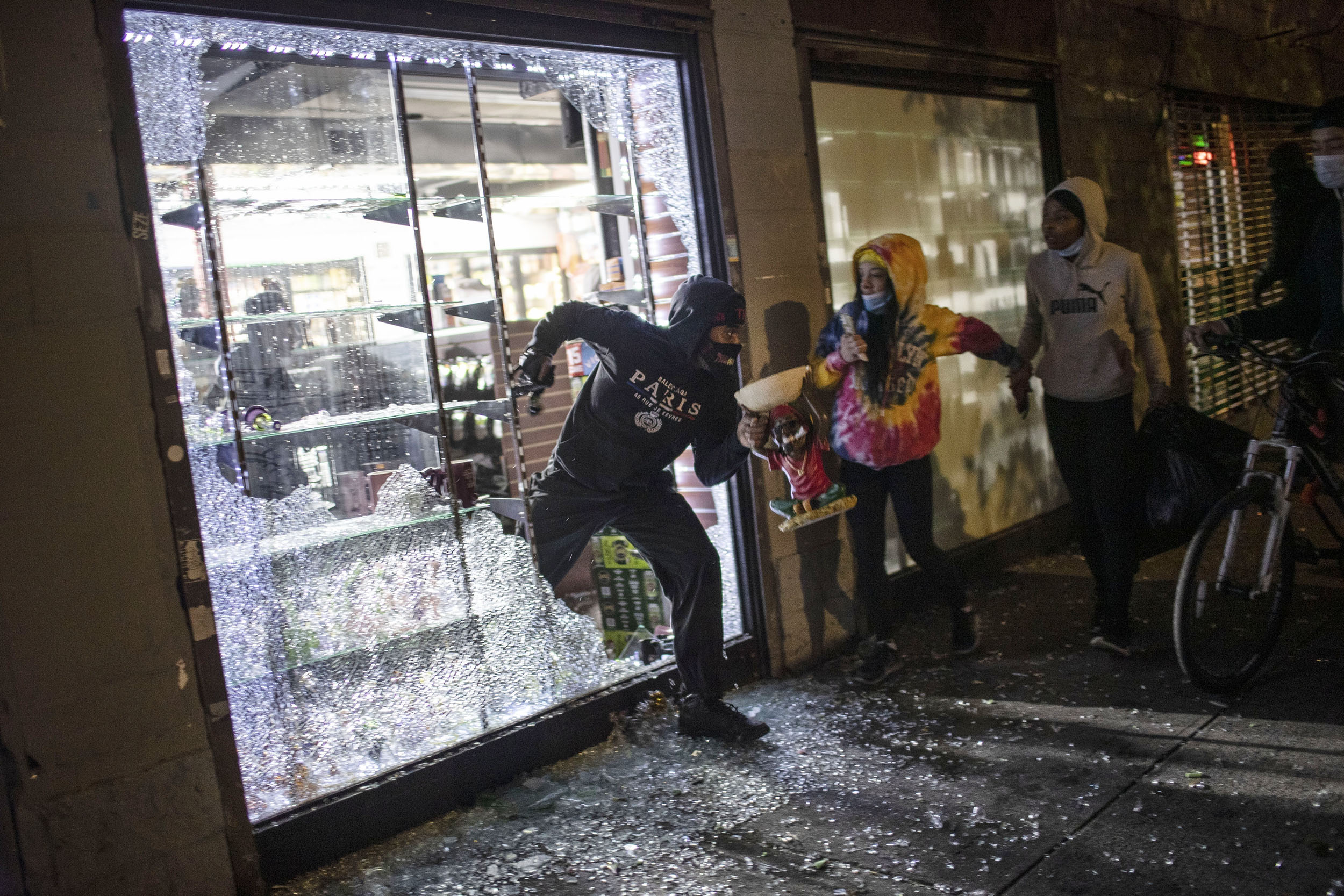 People run out of a smoke shop with smoking instruments after breaking in as police arrive in New York, on Monday, June 1. 