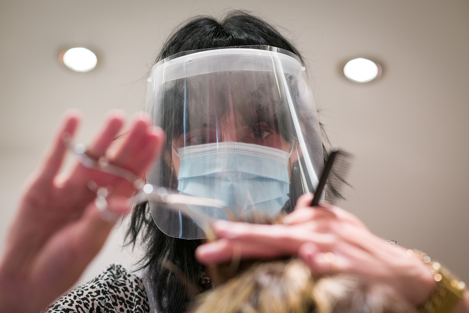 A stylist wears a protective face mask as she cuts a customer's hair at Tusk Hair stylists on July 4, in London.