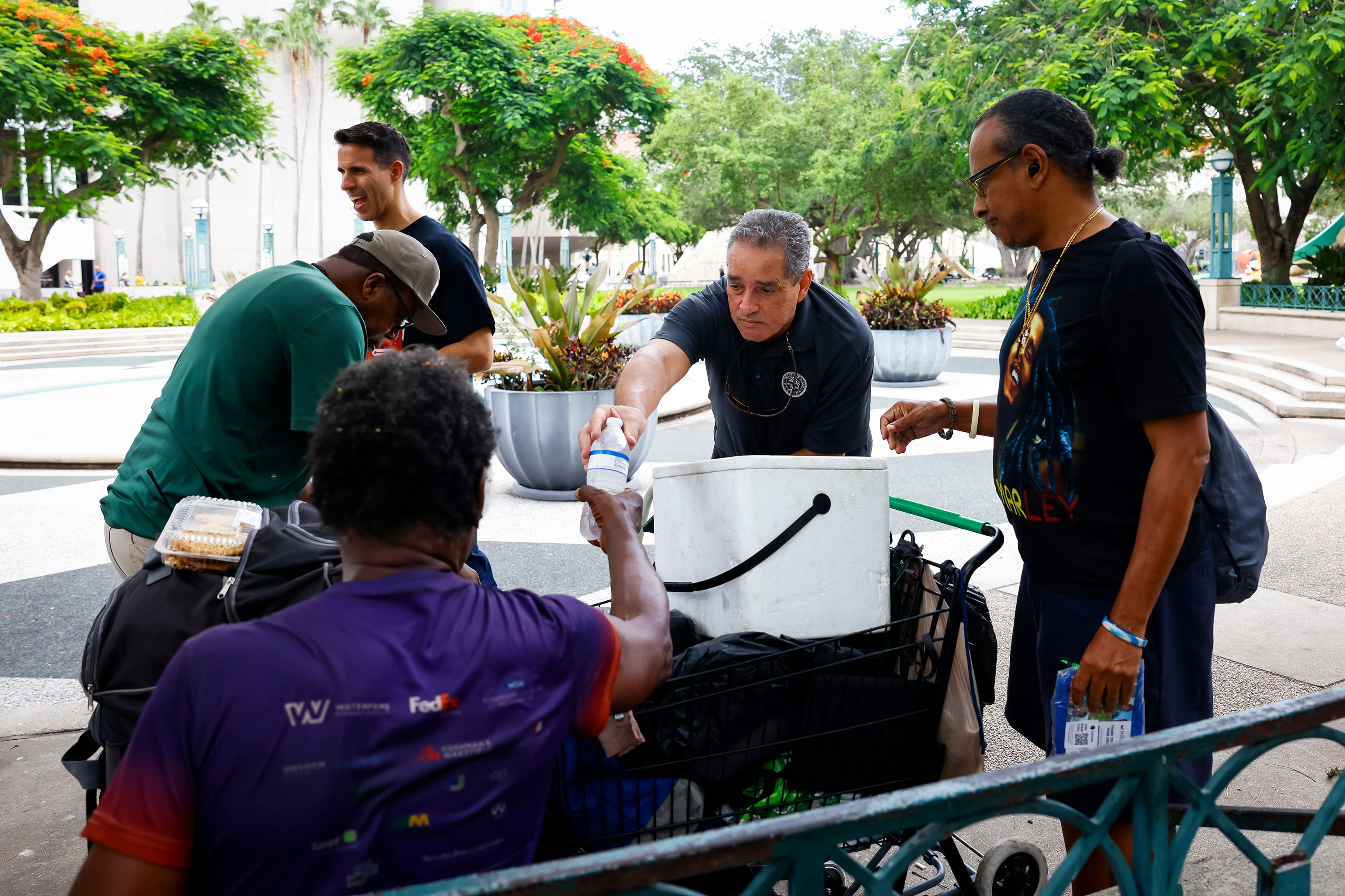 Representatives of the Miami-Dade County Homeless Trust distribute shelter information and bottles of water to people in Miami on July 25, 2023. 