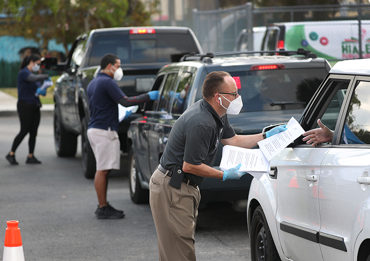 City of Hialeah employees hand out unemployment applications to people in their vehicles in front of the John F. Kennedy Library on Wedndesday,April 08,  in Hialeah, Florida. 