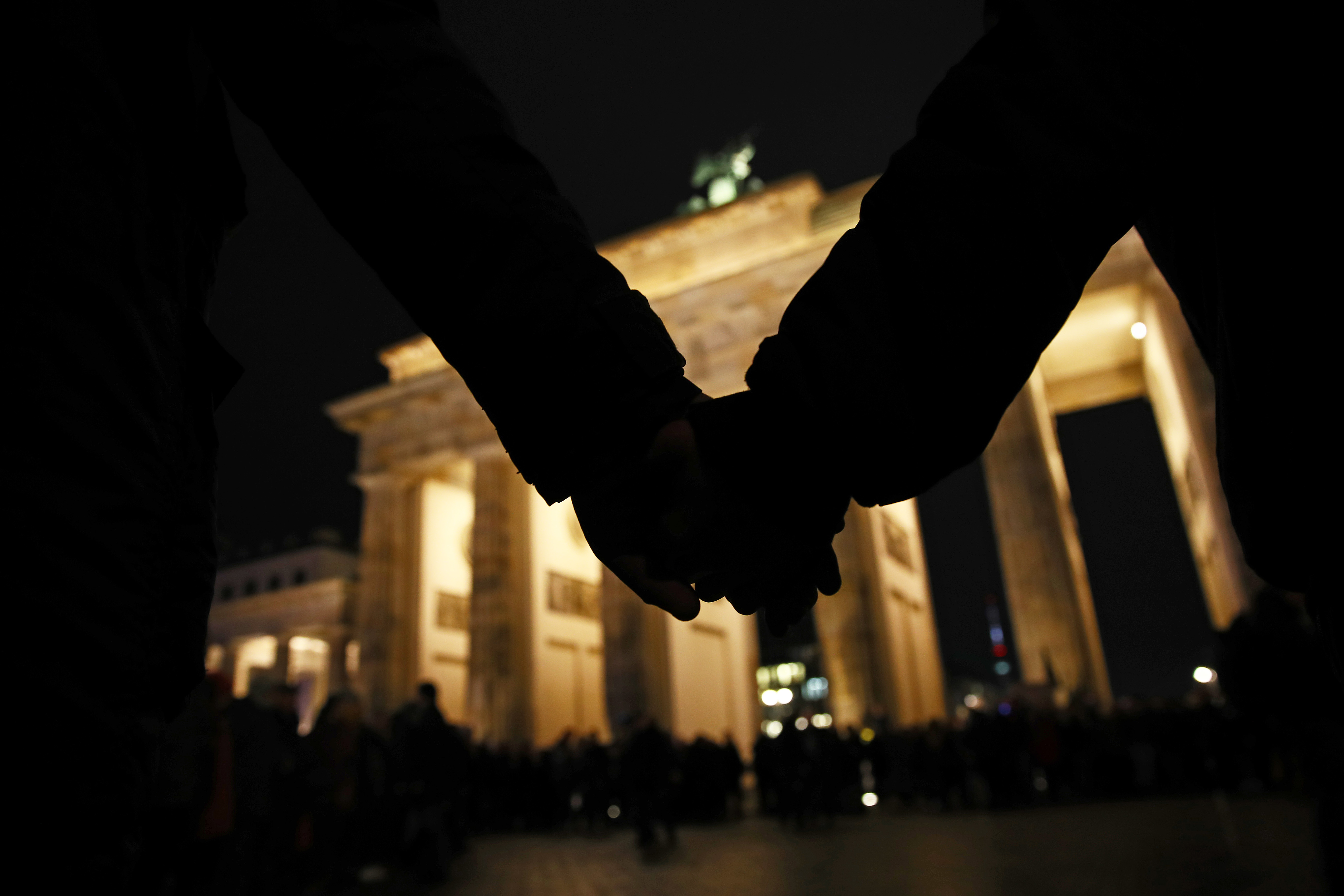  People hold hands during a vigil at the Brandenburg Gate to commemorate the victims of the Hanau shootings on Feb. 20 in Berlin.