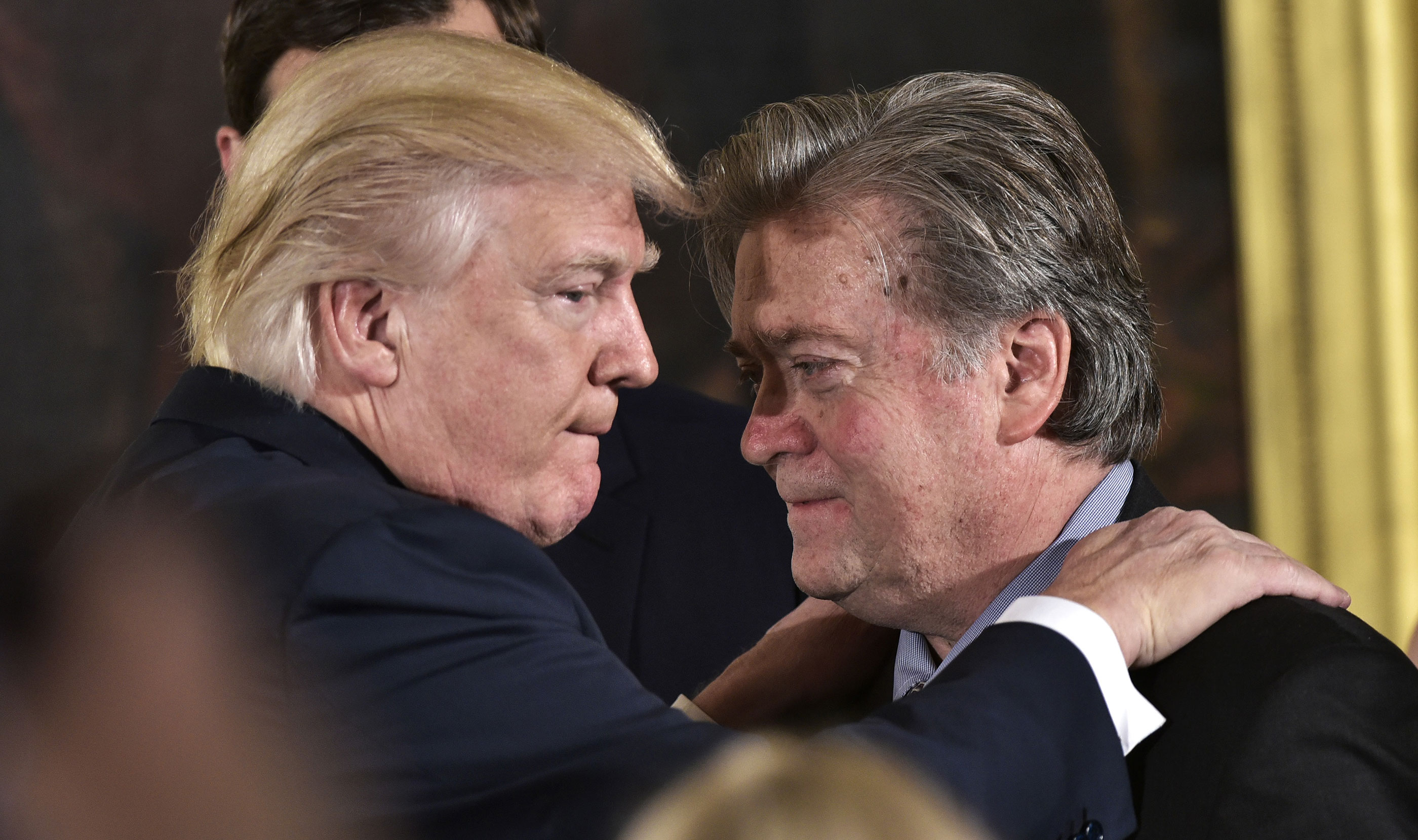 US President Donald Trump interacts with Steve Bannon during the swearing-in of senior staff at the White House on January 22, 2017 in Washington, D.C.